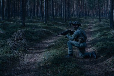 Özel kuvvetler askerleri tam teçhizatlı tüfekli ve gece görüş cihazlı gece devriye gezen ormanda miğfer takıyorlar..