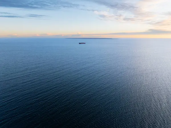 Günbatımında Baltık Denizi 'nin engin sularında yalnız bir gemi, sakin deniz yüzeyi ve uzak ufuk manzarası..