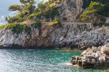 Gök Akdeniz suları ünlü bir Fransız tatil beldesi olan Cap Ferrat 'ın engebeli kıyılarına vuruyor..
