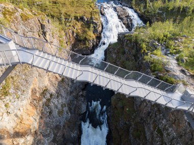 Norveç, insansız hava aracı görüşü: Voringsfossen şelalesi üzerindeki modern köprü, mimarinin ve vahşi kanyon doğasının nefes kesici bir birleşimi..