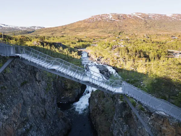 Çalkantılı Voringsfossen şelalesinin üzerinde ünlü bir köprü. Norveç 'in pitoresk dağlarında nefes kesici bir turistik cazibe..