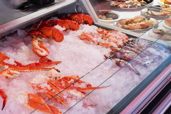 Norveç balık pazarının canlı görüntüsü, en taze deniz ürünlerinin bolluğunu gösteriyor: iştah açıcı ıstakozlar, yengeçler ve karides, ezilmiş buz üzerinde güzelce düzenlenmiş..