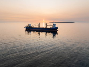 Günbatımında Baltık Denizi 'nde kargo gemisi, Estonya. Batan güneşin ışınlarında bir gemi olan sakin deniz manzarası, hava manzarası. Baltık doğası.
