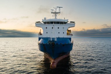 Görkemli insansız hava aracı görüntüsü: Baltık Denizi 'nde demirli bir yük gemisi altın bir gündoğumuna karşı.