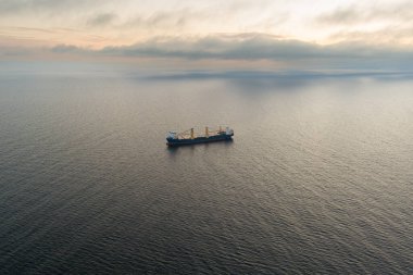 Gün batımında Baltık Denizi 'nde genel kargo gemisi, İHA atışı. Sakin deniz, yumuşak bulutlu gökyüzü.