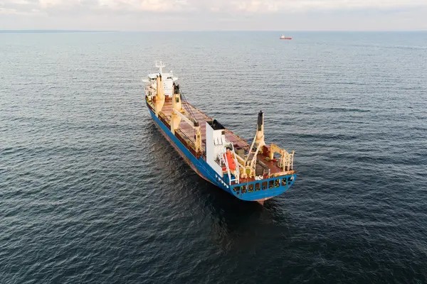 Estonya kıyıları yakınlarındaki Baltık Denizi 'nin sakin sularında yelken açan büyük mavi ve kırmızı bir genel kargo gemisinin hava manzarası..