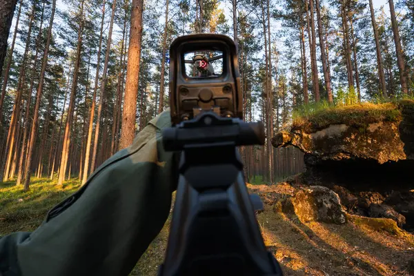 Birinci şahıs görüş: Bir nişancı, orman bölgesinde uçan bir drona holografik görüş açısı olan bir tüfeği hedef alır..