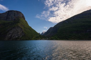 Norveç 'te, suya yansıyan sarp yeşil yamaçlarla nefes kesici bir fiyort manzarası ve küçük bir köy..