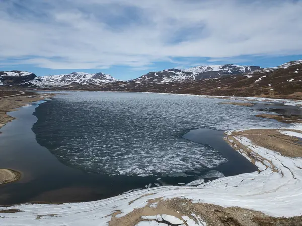 Norveç 'teki Hallingskarvet Ulusal Parkı' ndaki Kjelavatn Gölü 'ndeki buzların eriyişini gösteren insansız hava aracı manzarası görkemli dağların ortasında..