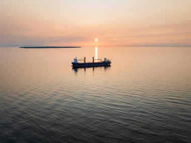 Baltık Denizi 'nin sakin sularında gün batımında bir kargo gemisinin insansız hava aracı görüntüsü. 