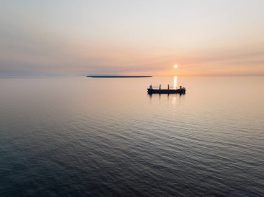 Günbatımında Estonya adında küçük bir adayla Baltık Denizi 'nde kargo gemisi..