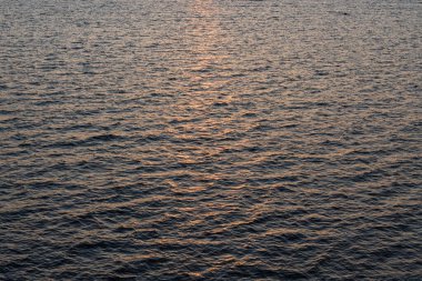 Baltık Denizi üzerinde gün batımı: altın dalgalar ve güneş karanlık su yüzeyinde parlıyor sakin bir doğal zemin oluşturur.