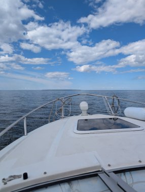 Berrak bir yaz gününde bulutlarla birlikte Estonya açıklarında sakin Baltık Denizi 'nde yelken açan beyaz bir yatın pruvası..