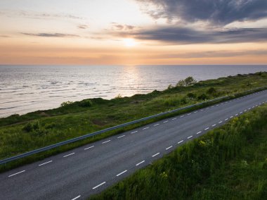 Günbatımında Estonya 'da Baltık Denizi kıyısında manzaralı bir otoyol manzarası. Yaz gezisi için mükemmel bir yol..