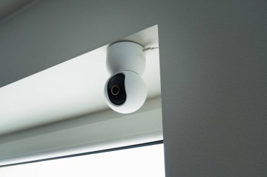 Akıllı bir ev sisteminin modern PTZ IP kamerası. 7 / 24 izlenmek üzere tavana yerleştirilmiş beyaz bir gözetleme kamerası.