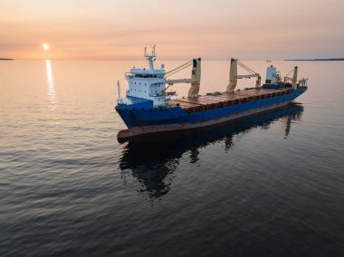 Estonya açıklarındaki sakin Baltık Denizi 'ne demir atmış büyük bir kargo gemisinin hava görüntüsü. Güzel, sakin bir günbatımında..