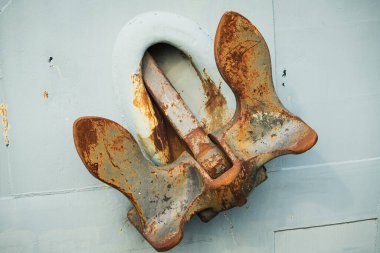 Pas ve metal dokusu. Geminin gövdesinin gri arka planına karşı eski bir geminin çapasına yakın çekim..