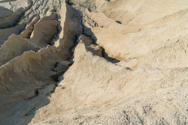 Parlak güneş ışığı altında kumlu, kurak ve desenli bir arazide minyatür kanyonlar ve vadiler oluşturan şiddetli toprak erozyonunun ayrıntılı görüntüleri..
