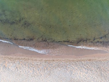 Baltık Denizi kıyı şeridinin yukarıdan aşağı sakin havası yumuşak, kumlu kumsalın üzerinde hafif şeffaf dalgalar süzülüyor..