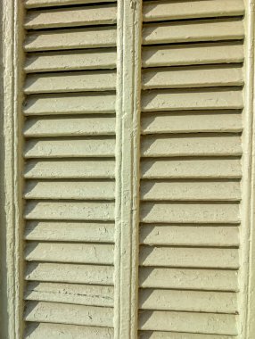 Eski ahşap panjurlu mimari arka plan. Güneş ışığında çatlamış boya ve desenli vintage levhalara yakın çekim.