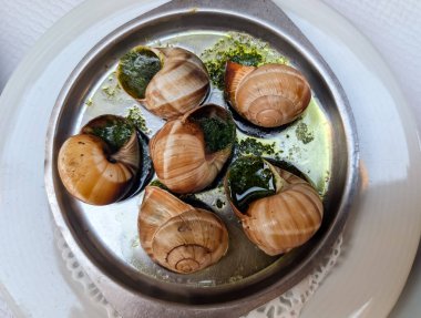 Salyangoz de Bourgogne, Fransız mutfağının geleneksel aperatifi. Özel bir tabakta sarımsaklı tereyağı ve maydanozlu kabuklu fırında salyangoz..