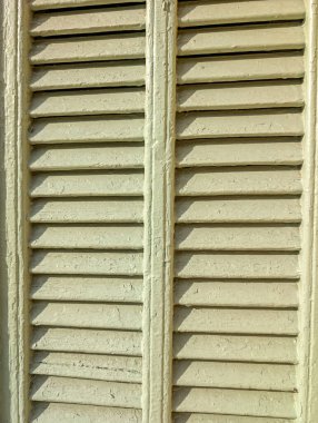 Eski ahşap panjurlu mimari arka plan. Güneş ışığında çatlamış boya ve desenli vintage levhalara yakın çekim.