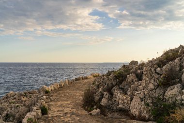 Fransa 'daki Saint-Jean-Cap-Ferrat yarımadasının kayalık Akdeniz kıyıları boyunca kıvrılan antik taş patika..