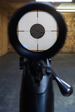 Sürgülü tüfeğin teleskopik görüşünden birinci şahıs görüş, kapalı bir menzili hedef alan bir kağıt hedefe nişan alıyor..