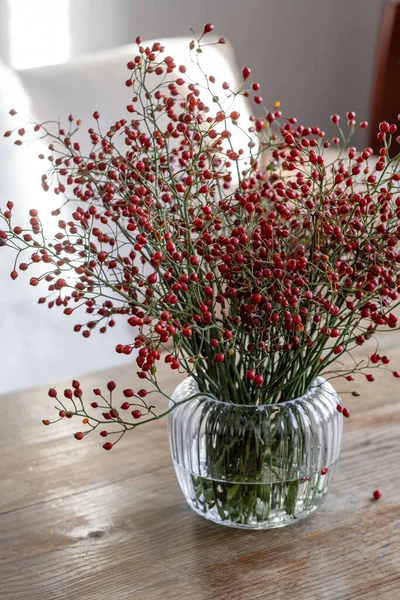 Berrak bir vazoda, bir buket multiflora (meyve dalları).