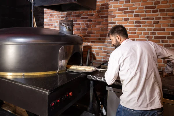 Pita turtalarını fırına koyarken Aşçı Kameraya Bakıyor