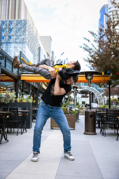 Baba ve Oğul, şehirdeki kafelerin önünde gülüp eğleniyorlar.