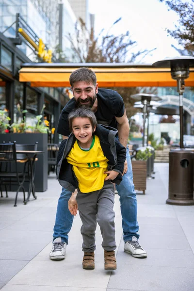 Baba ve Oğul, şehirdeki kafelerin önünde gülüp eğleniyorlar.