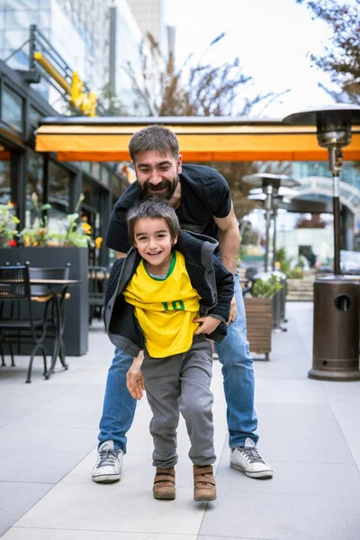 Baba ve Oğul, şehirdeki kafelerin önünde eğleniyor. Gülüyor.