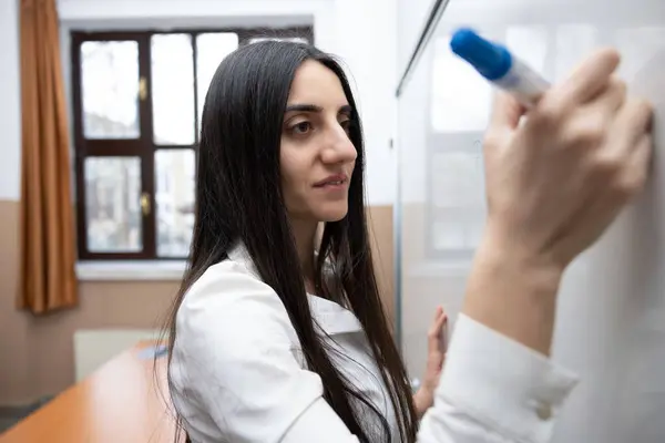 Bayan öğretmen sınıftaki boş tahtaya yazı yazmaya başladı. Kapatın.