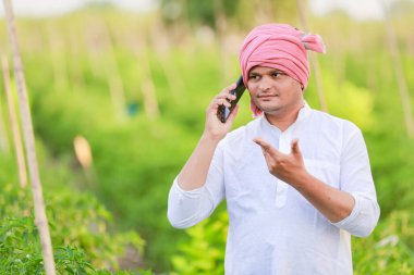 Genç Hintli çiftçi akıllı telefon gösteriyor, çiftçi telefonda konuşuyor, mutlu Hintli çiftçi.