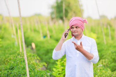 Genç Hintli çiftçi akıllı telefon gösteriyor, çiftçi telefonda konuşuyor, mutlu Hintli çiftçi.
