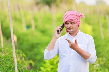 Genç Hintli çiftçi akıllı telefon gösteriyor, çiftçi telefonda konuşuyor, mutlu Hintli çiftçi.