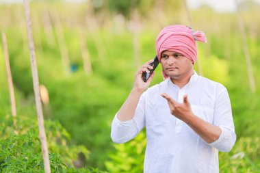 Genç Hintli çiftçi akıllı telefon gösteriyor, çiftçi telefonda konuşuyor, mutlu Hintli çiftçi.