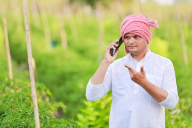 Genç Hintli çiftçi akıllı telefon gösteriyor, çiftçi telefonda konuşuyor, mutlu Hintli çiftçi.