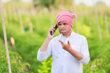 Genç Hintli çiftçi akıllı telefon gösteriyor, çiftçi telefonda konuşuyor, mutlu Hintli çiftçi.