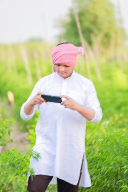 Genç Hintli çiftçi akıllı telefon gösteriyor, çiftçi telefonda konuşuyor, mutlu Hintli çiftçi.