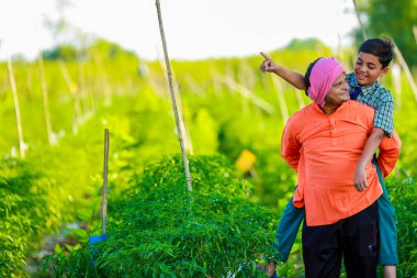 Şirin Hintli çiftçi çocuk. Okul üniformalı. Babası tarlada, mutlu baba ve oğlu.