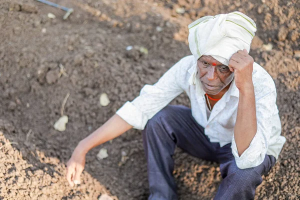 sad farmer, Elderly farmer man sitting in the soil & lost in thought very deeply. He is wearing traditional Indian clothes