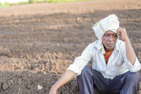sad farmer, Elderly farmer man sitting in the soil & lost in thought very deeply. He is wearing traditional Indian clothes