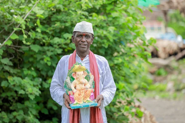 Hintli yaşlı adam Ganesha 'yı elinde tutuyor, mutlu yaşlı adam.