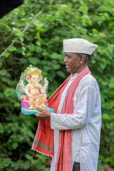 stock image Indian old man holding Lord Ganesha idol in hands , happy old poor man