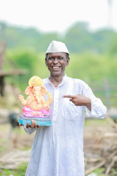 stock image Indian old man holding Lord Ganesha idol in hands , happy old poor man