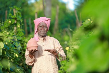 Çiftlikte domuz kumbarası tutan Hintli çiftçi mutlu çiftçi, fakir çiftçi, çiftçi tasarruf