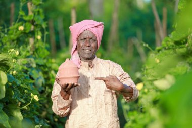 Çiftlikte domuz kumbarası tutan Hintli çiftçi mutlu çiftçi, fakir çiftçi, çiftçi tasarruf