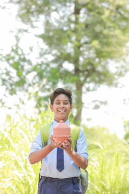 Hintli akıllı çocuk geleneksel domuz kumbarası veya Gullak, Yatırım ve bankacılık kavramını elinde tutuyor.
